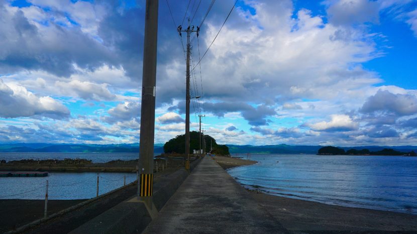 熊本県上天草市、小島公園キャンプ場へと続く海の中の一本道と並び立つ電柱の風景
